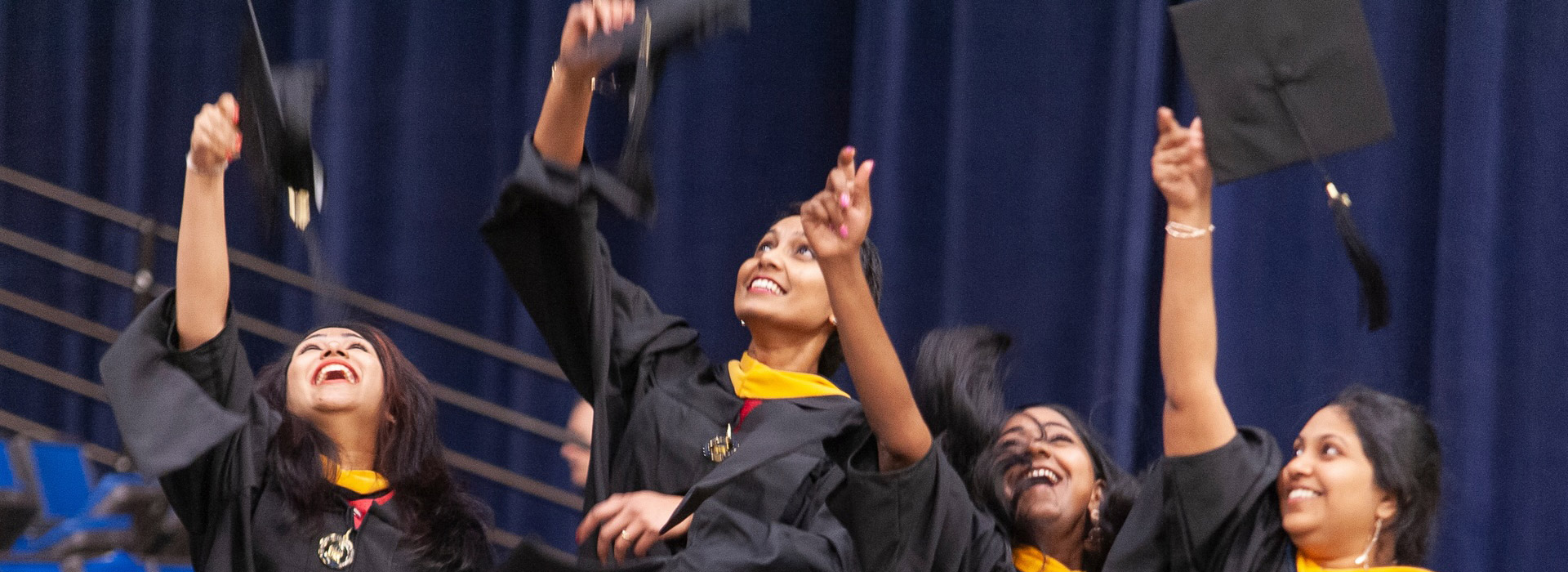 graduates throwing their caps up in the air in celebration