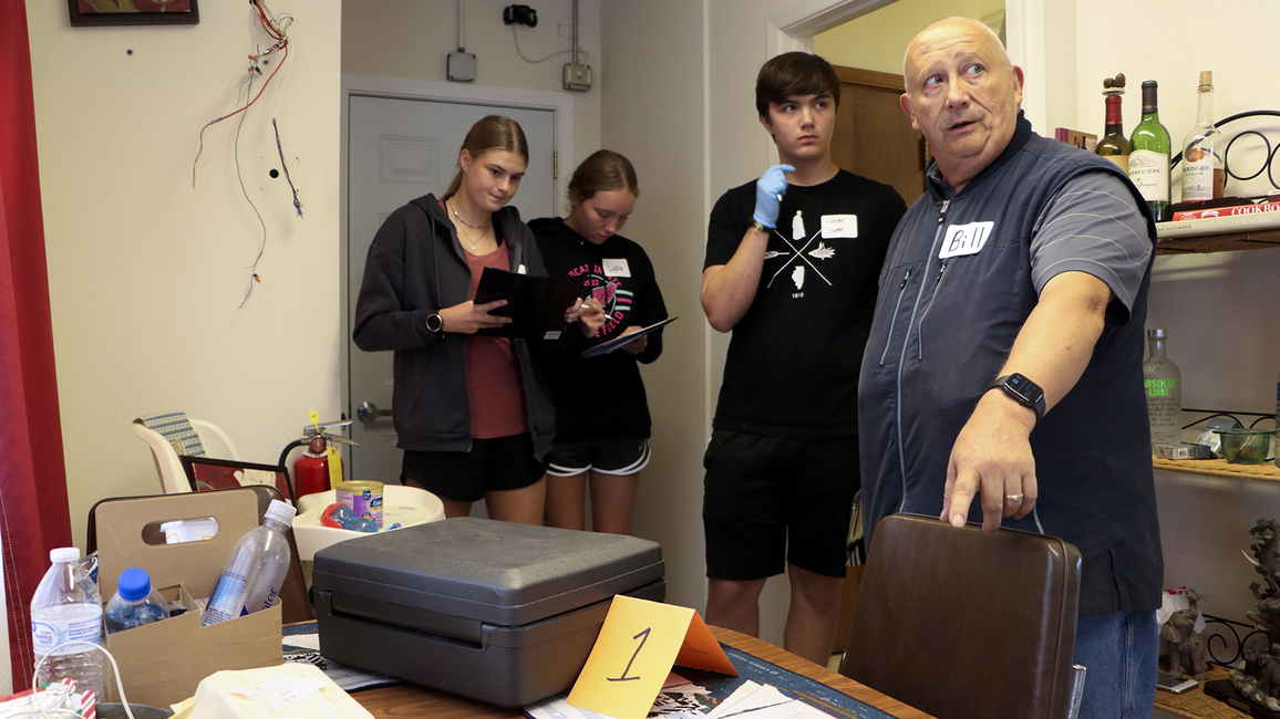 Students and an instructor investigate clues during a CSI camp.