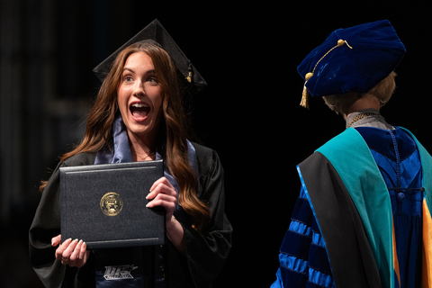 a visibly excited graduate receiving her degree from the chancellor 