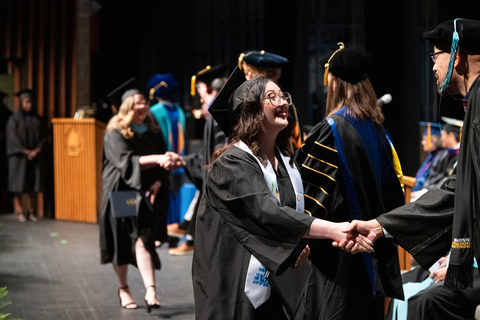 line of graduate shaking hands with professors on stage