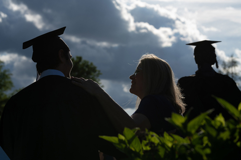 a graduate and their family silhouetted by the sun