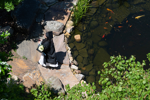 bird's eye view of a graduate in their regalia hanging out by the pond in front of HSB