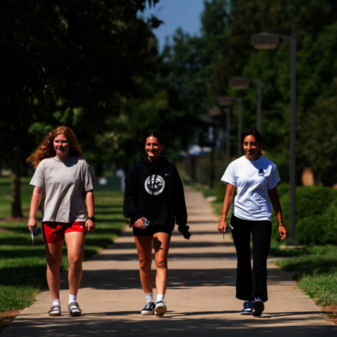 three students walking on the quad