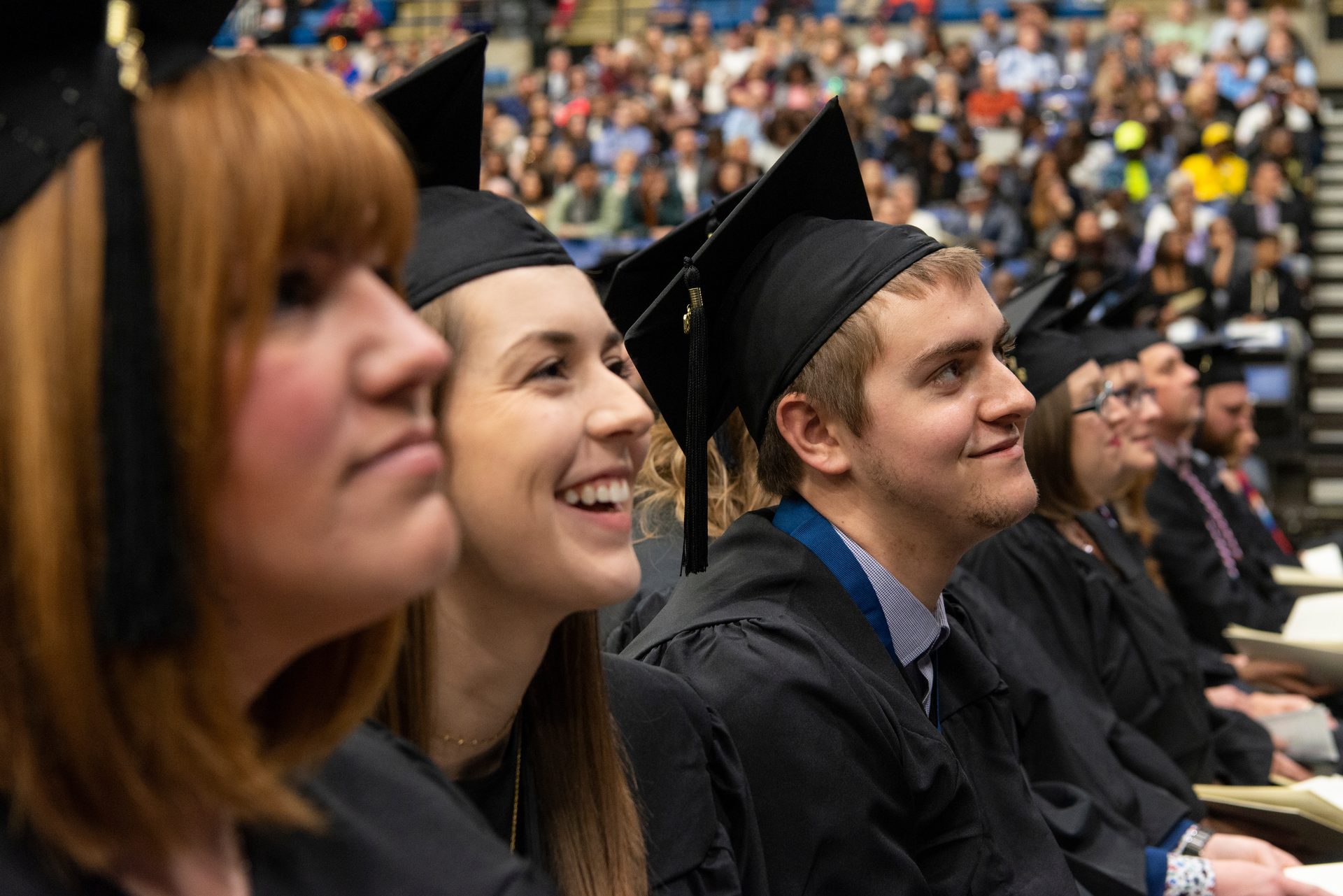 Several students listen to a speaker at a graduation ceremony