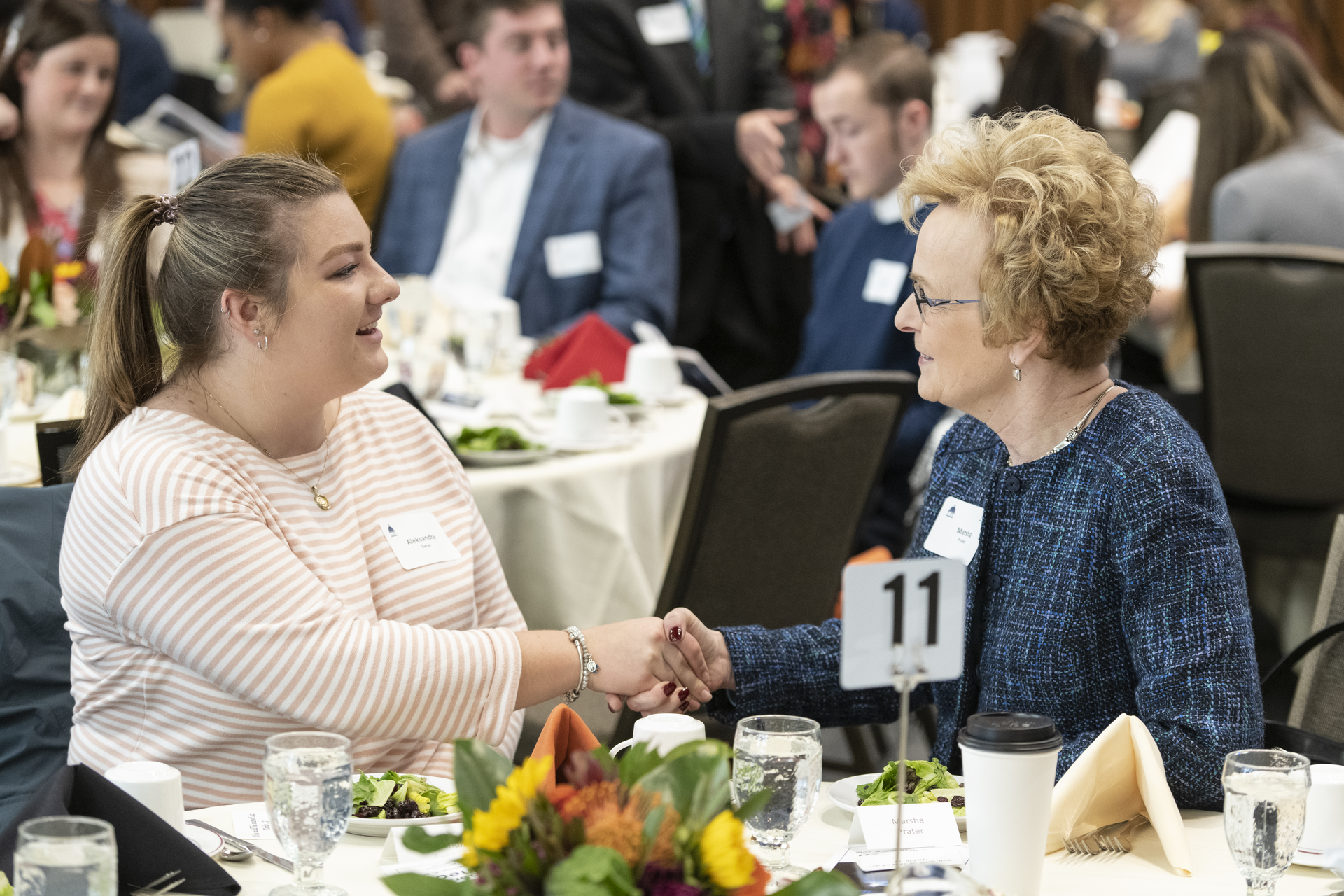 A woman and female student sitting at a table talking at a UIS Scholarship luncheon.