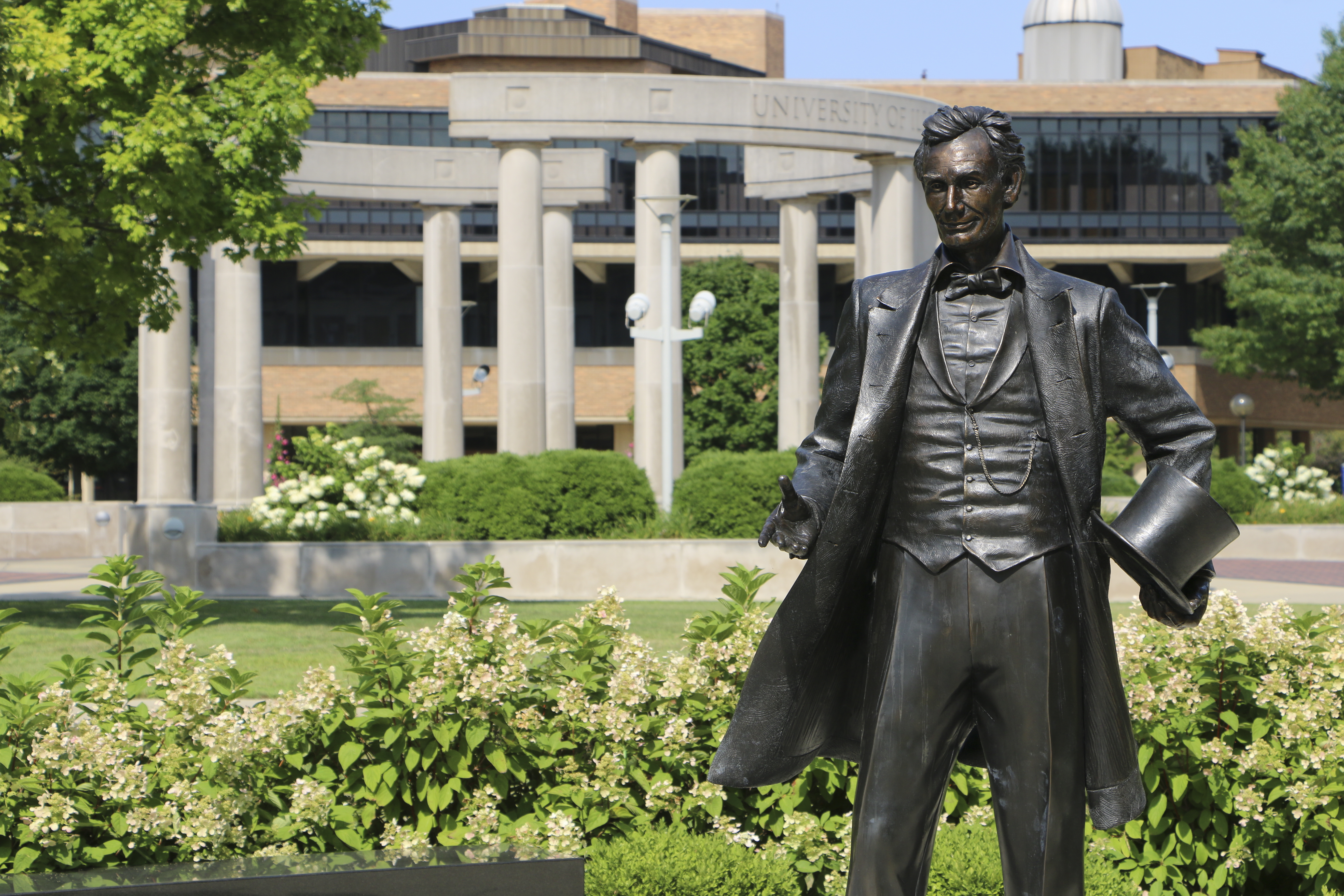 Summer foliage with statue of Abe Lincoln in foreground and colonnade in background.