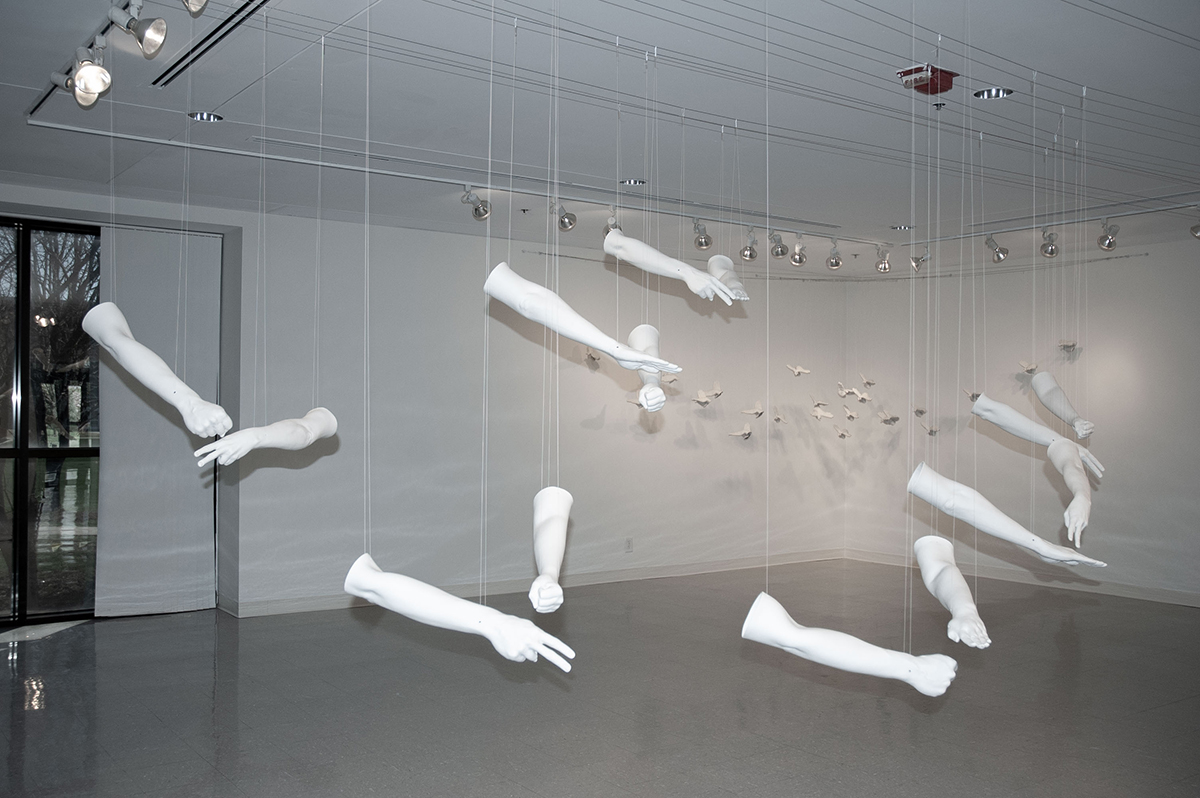 artwork of hanging ceramic arms playing rock, paper, scissors