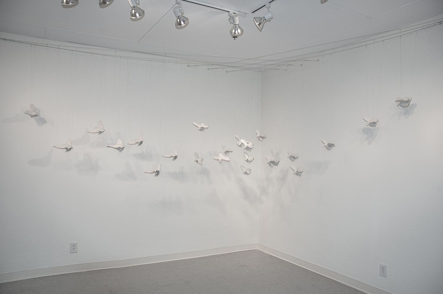 artwork of lots of hanging ceramic hands imitating birds flying