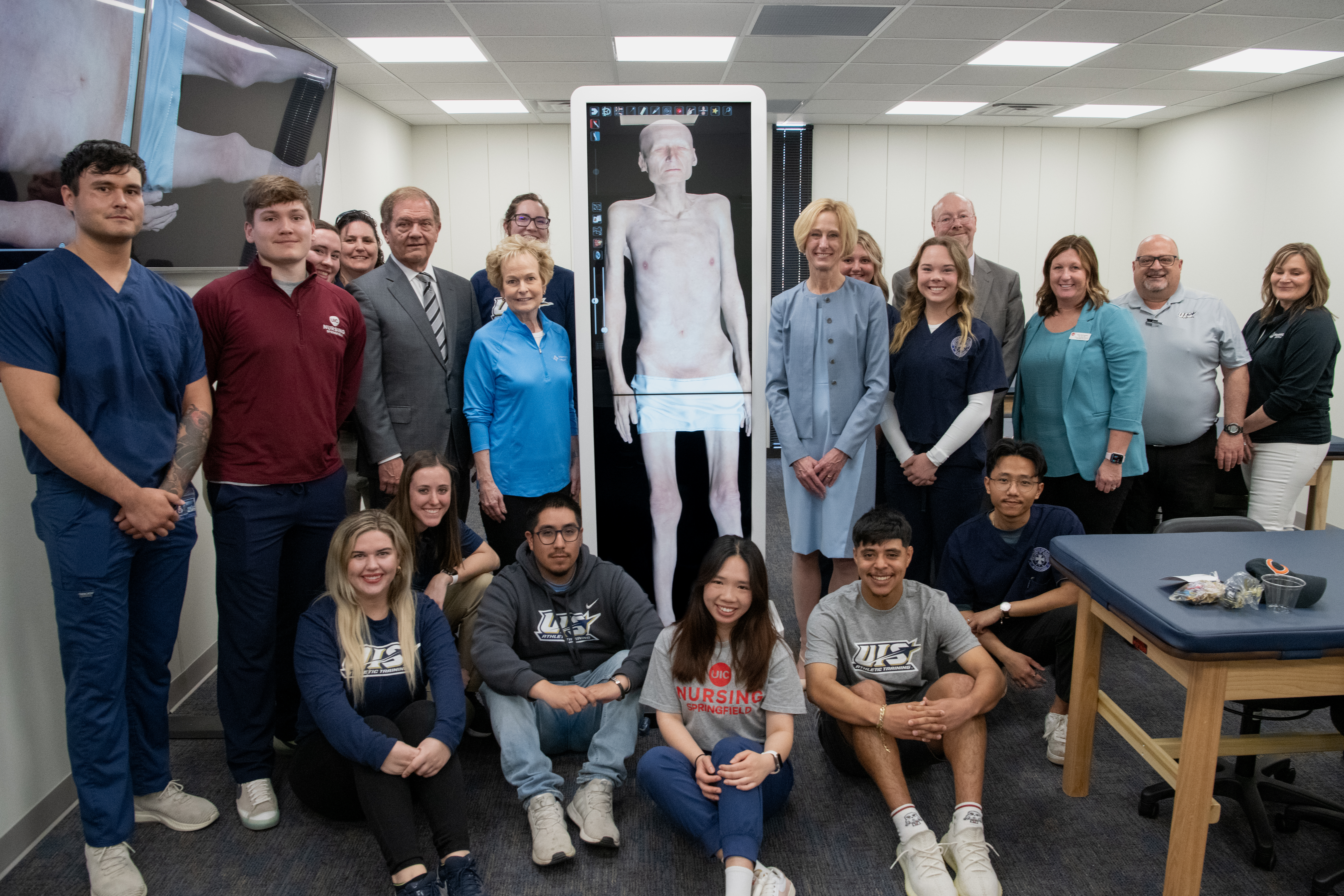 UIS students and leaders gathered around an Anatomage table displaying a 3D image of a human.