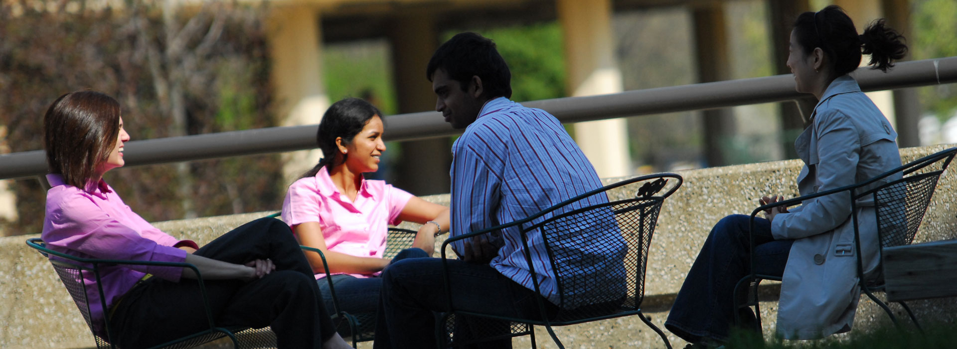 four students sitting out on the quad talking with each other