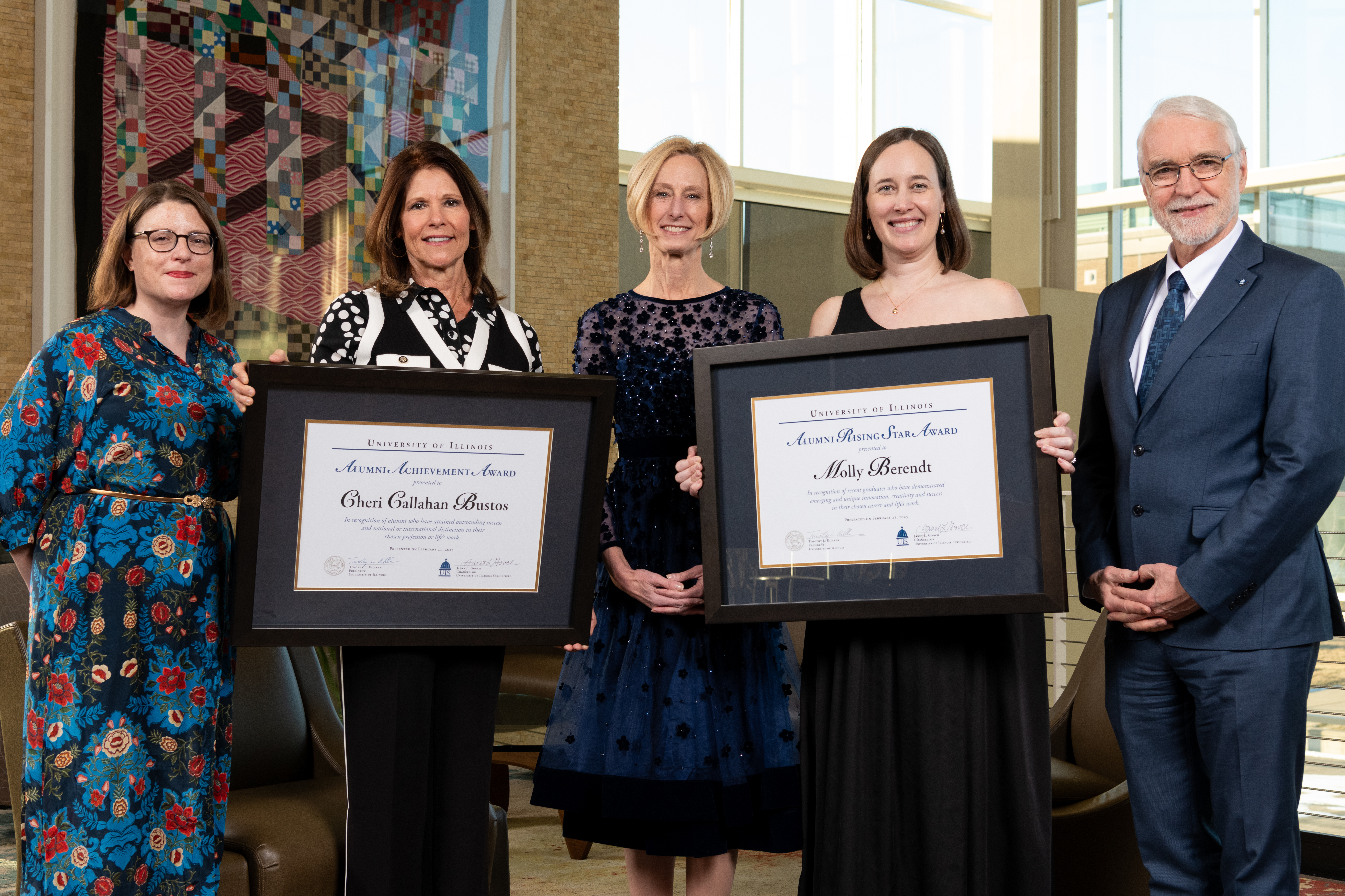 two awardees holding their awards pose with UIS alumni board chair, chancellor and system president