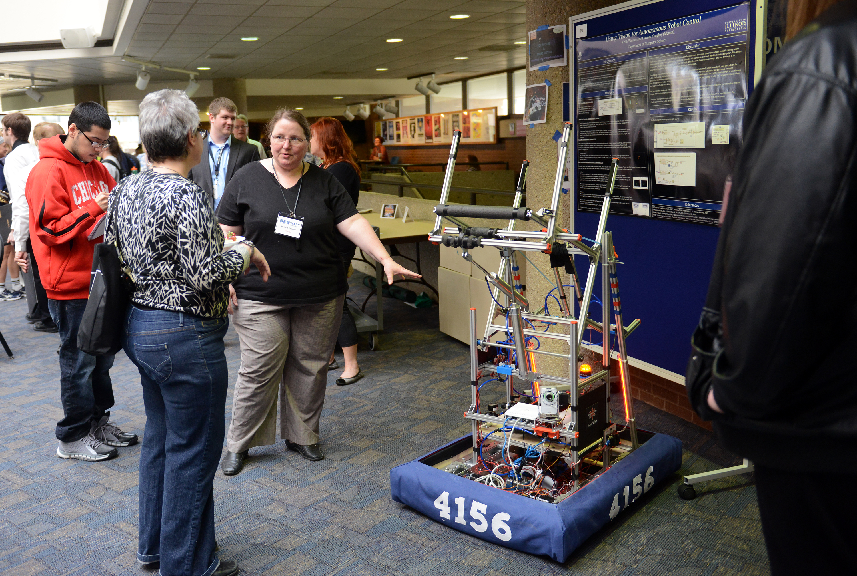 A campus research fair gestures toward a student-built robot