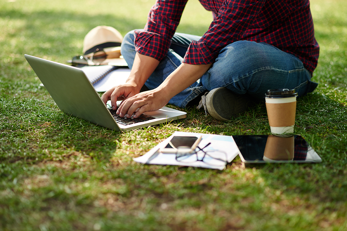 Student creating a learning portfolio on a laptop outdoors at UIS