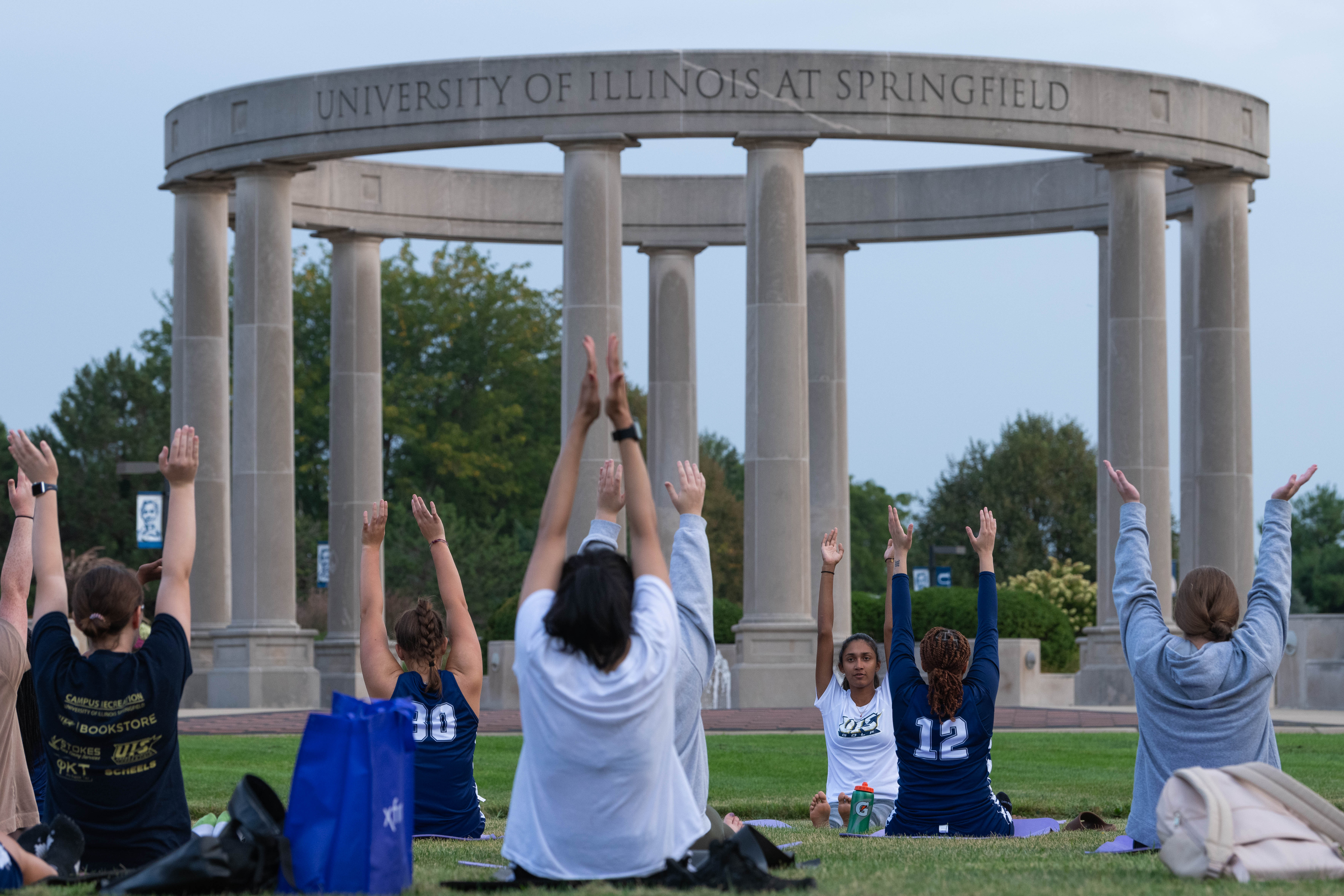 Student doing yoga on the quad in front of the colonnade 