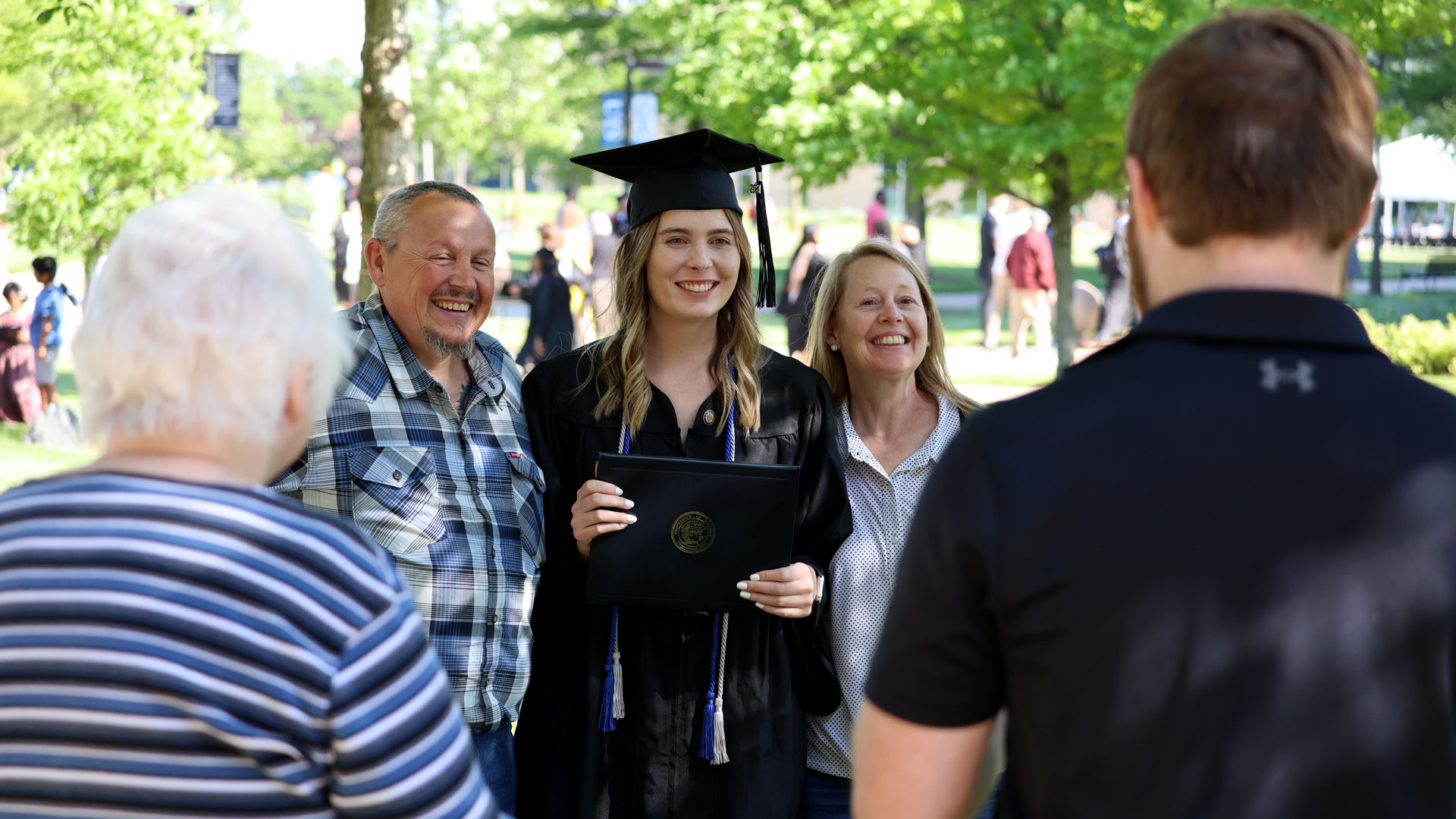 a female graduate in cap and gown posing with her parents
