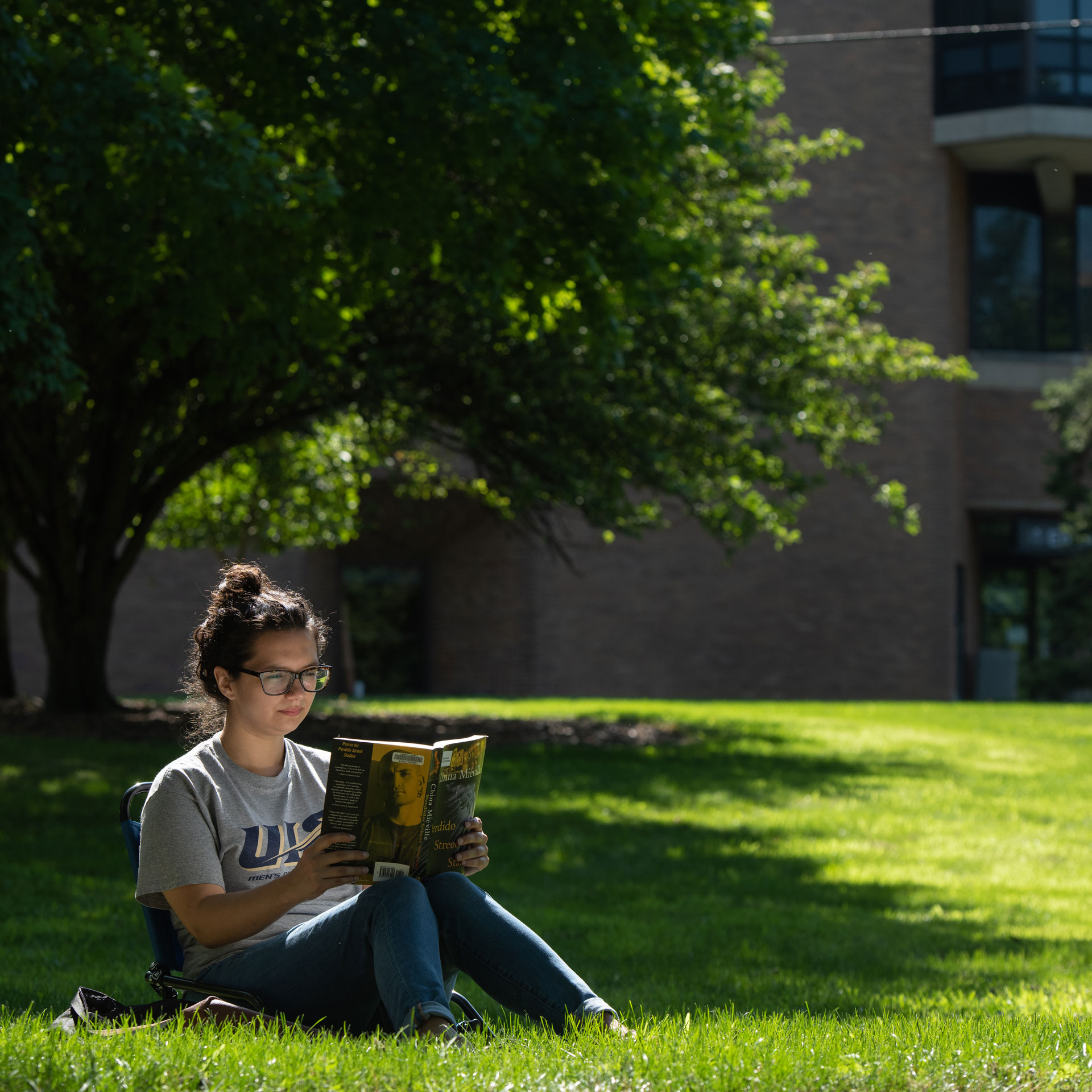 a student reading a book on the quad