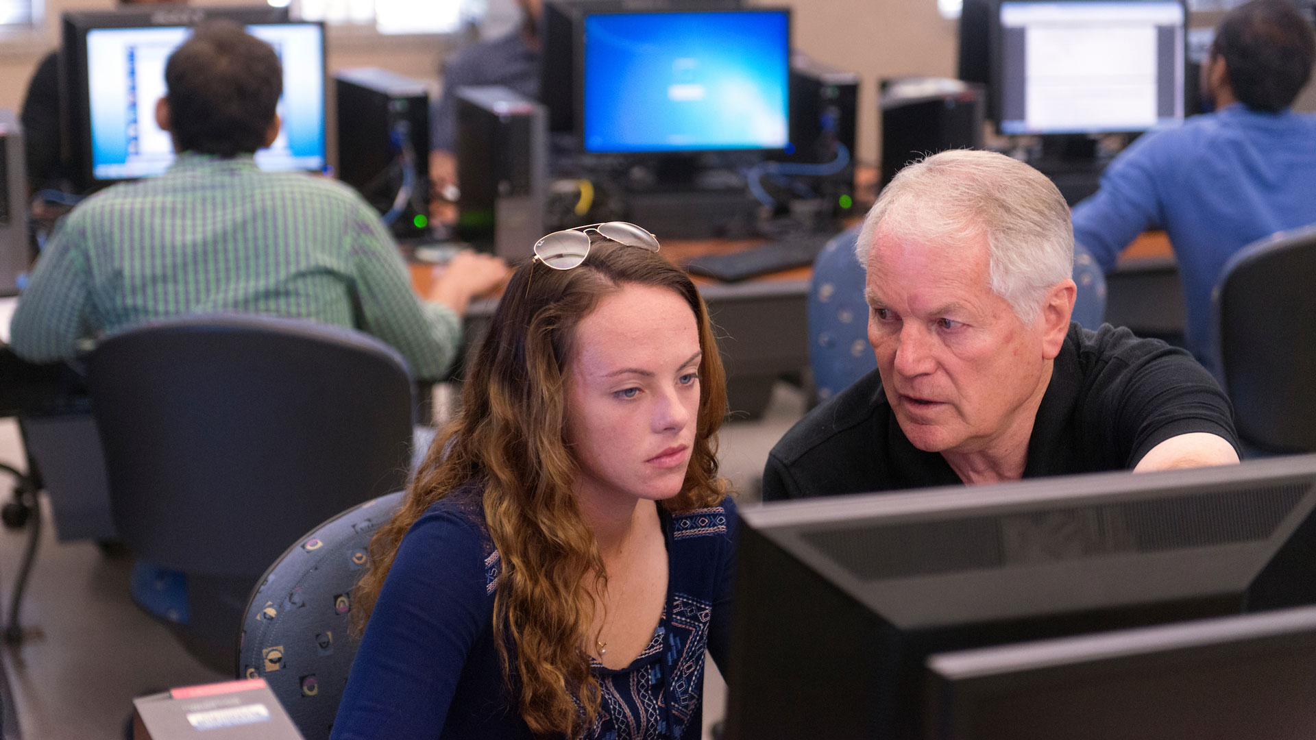 a professor explaining something on a computer to a student