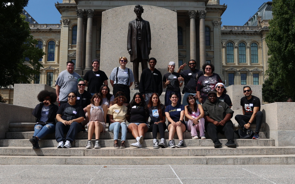 Group of people standing in front of an Abraham Lincoln Statue outside of the Capitol Building.