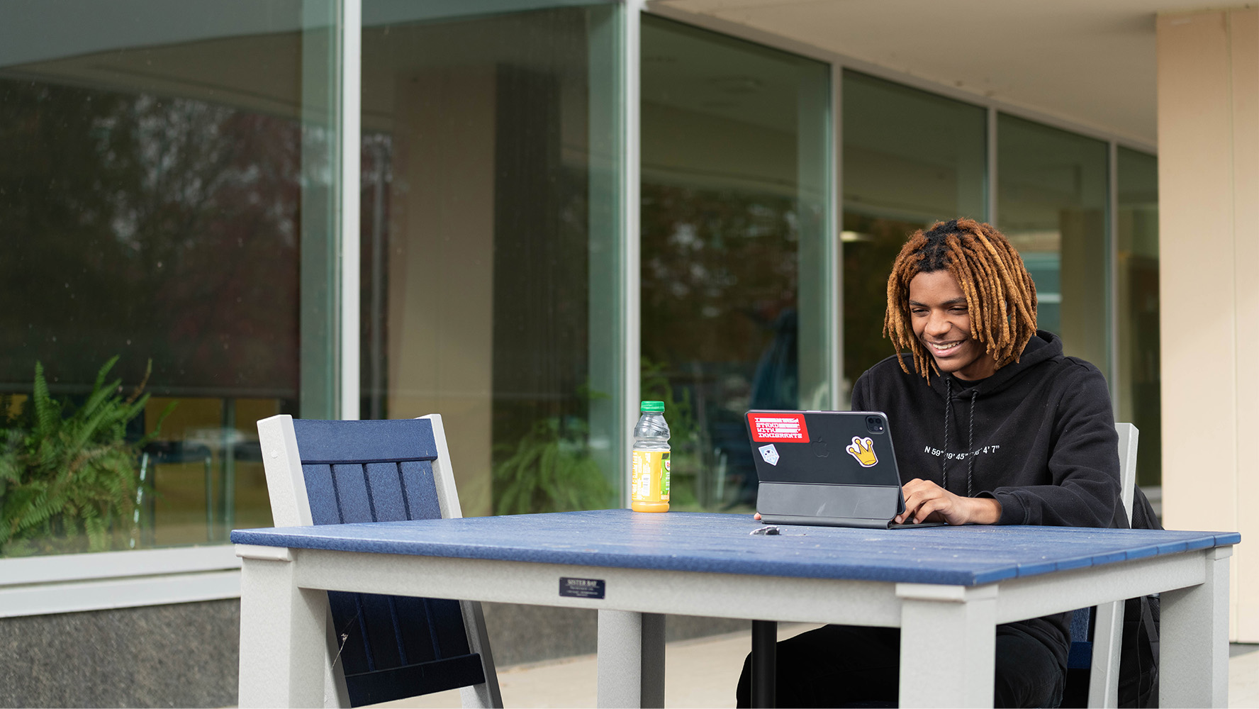 Student studying outdoors on a laptop at a campus table