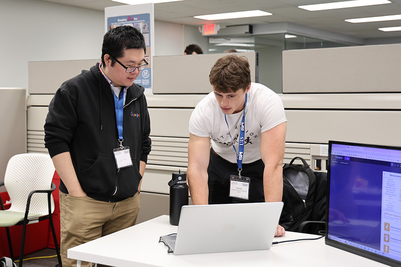Students collaborating at a laptop in campus workspace