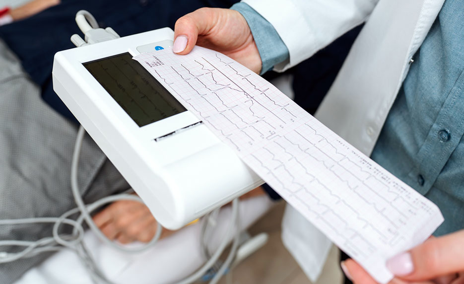Doctor holds ECG printout from machine.