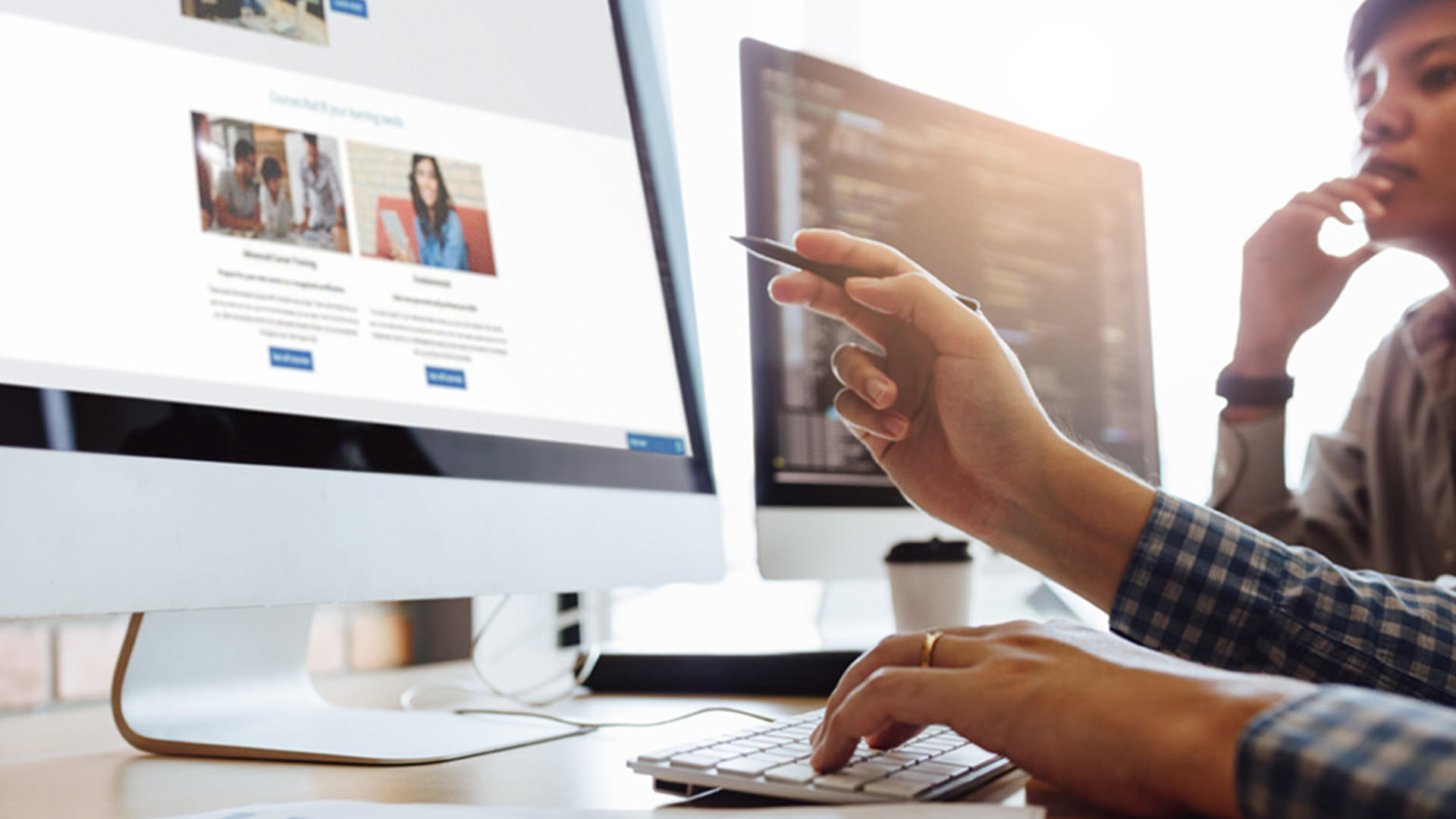 Two people at computers discussing code and website content.