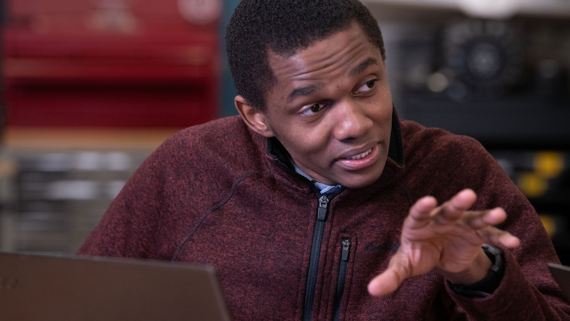a student at his laptop explaining a concept to someone off-screen