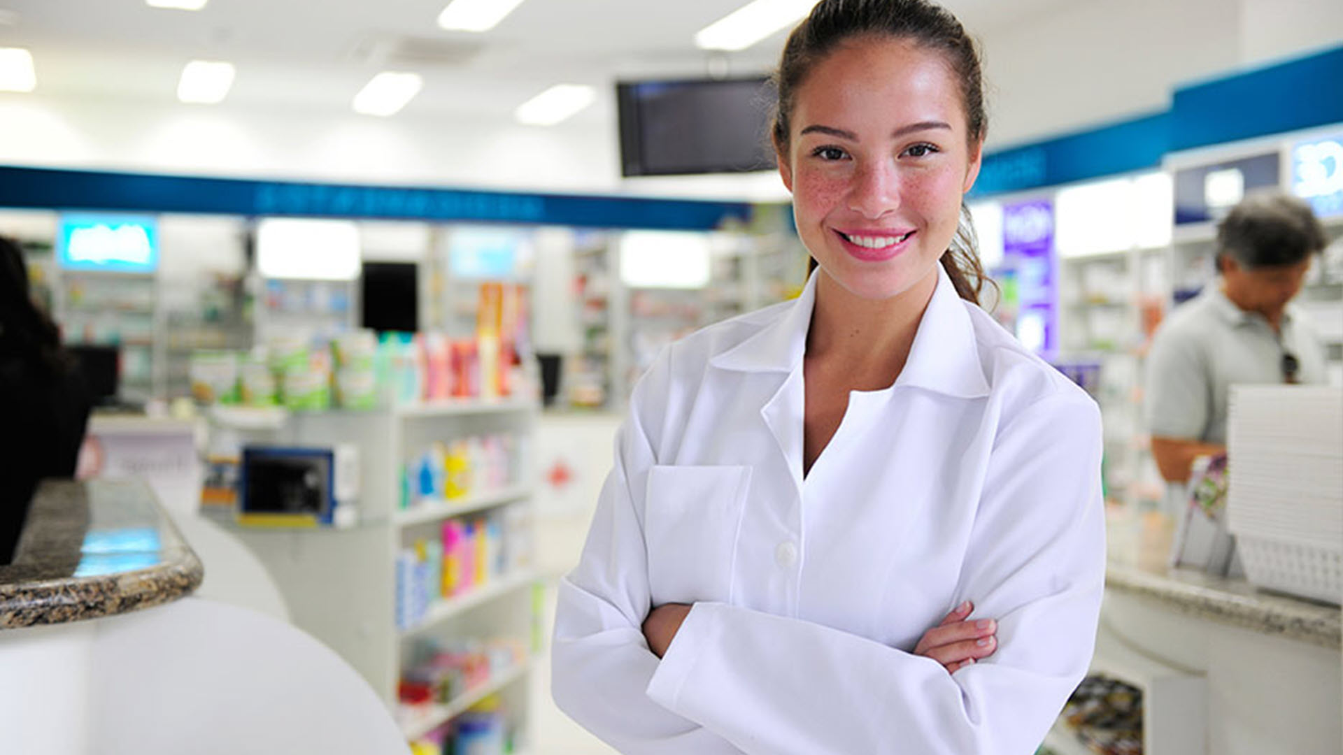Pharmacist smiling in a brightly lit pharmacy.