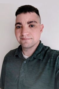 Casual portrait of a man in a dark shirt against a plain background.