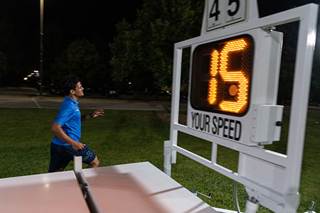 Student running at night next to sign showing 15MPH