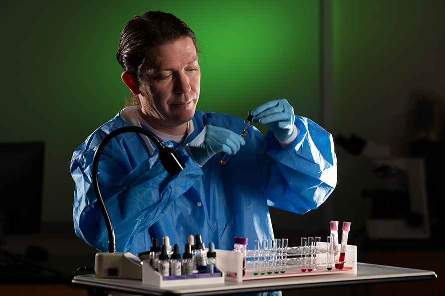 student in lab coat adding liquid in test tube