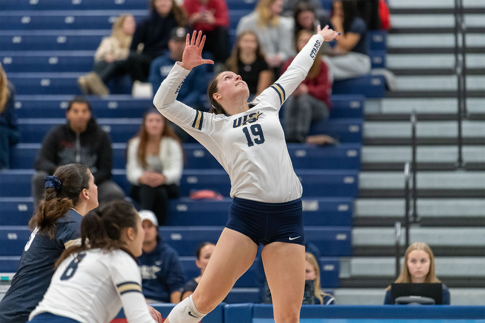 UIS volleyball player serving during a match