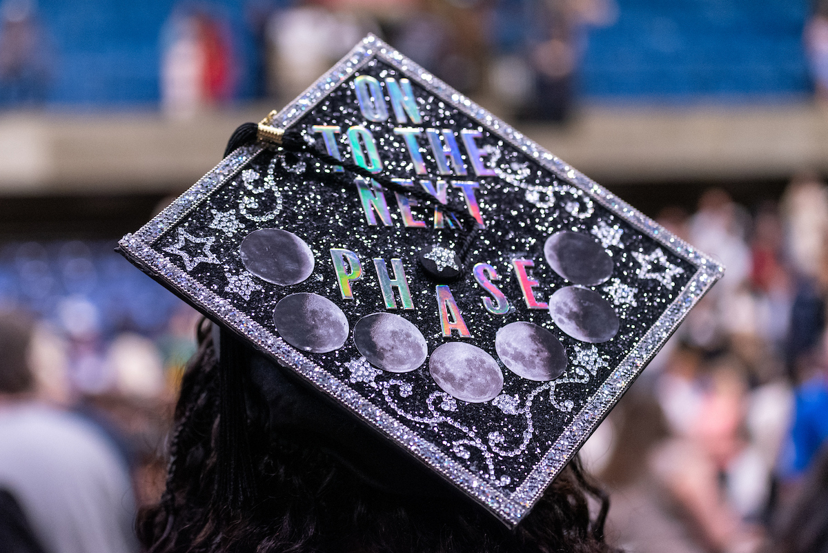 grad cap with On to the next phase and moons on board