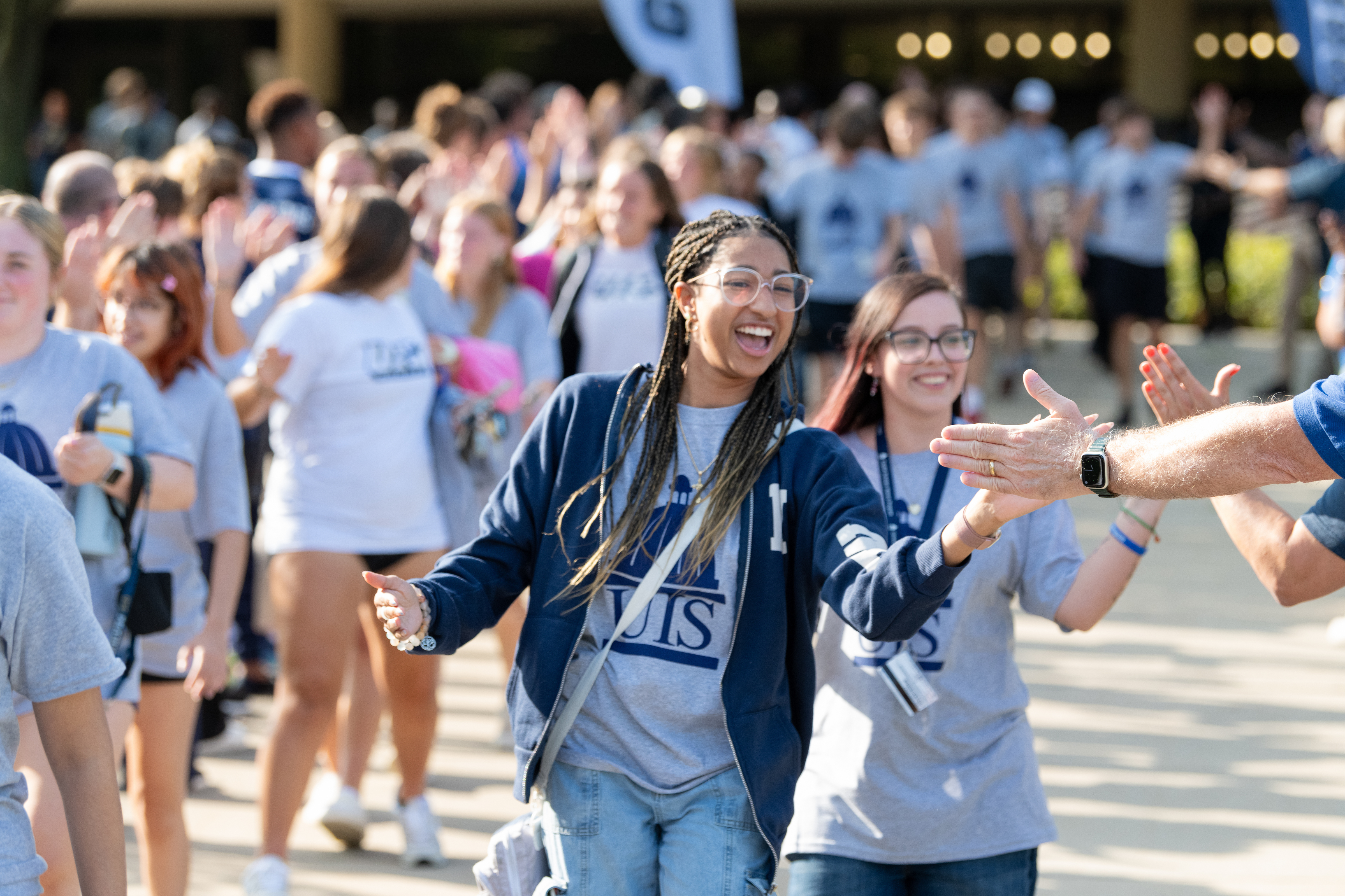 UIS students in matching shirts smiling and high-fiving at new student convocation