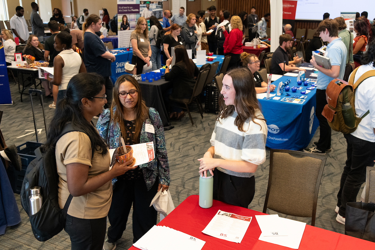 Students and employers talking at a booth at a career fair