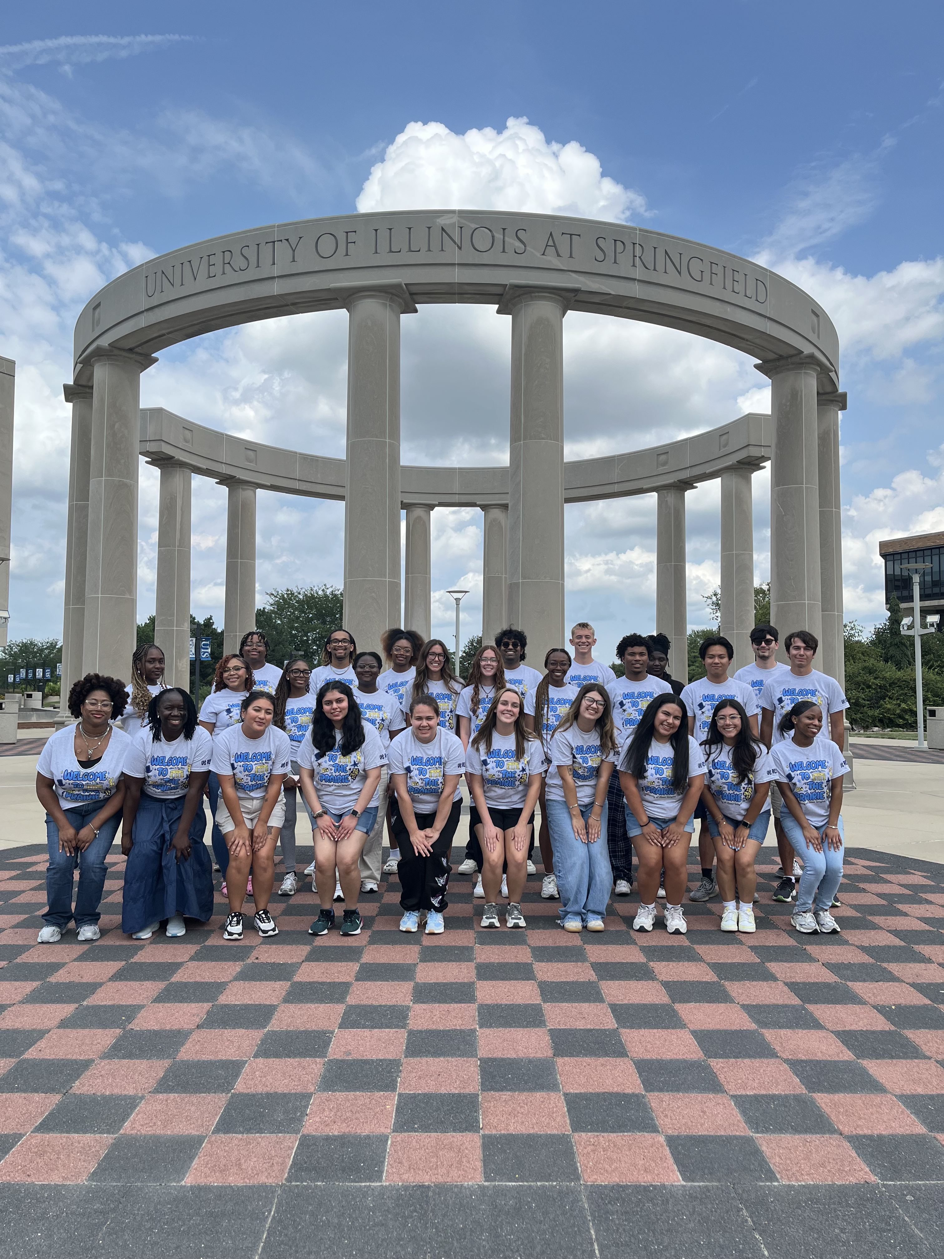 Resident Assistants under colonnade with cloudy sky.