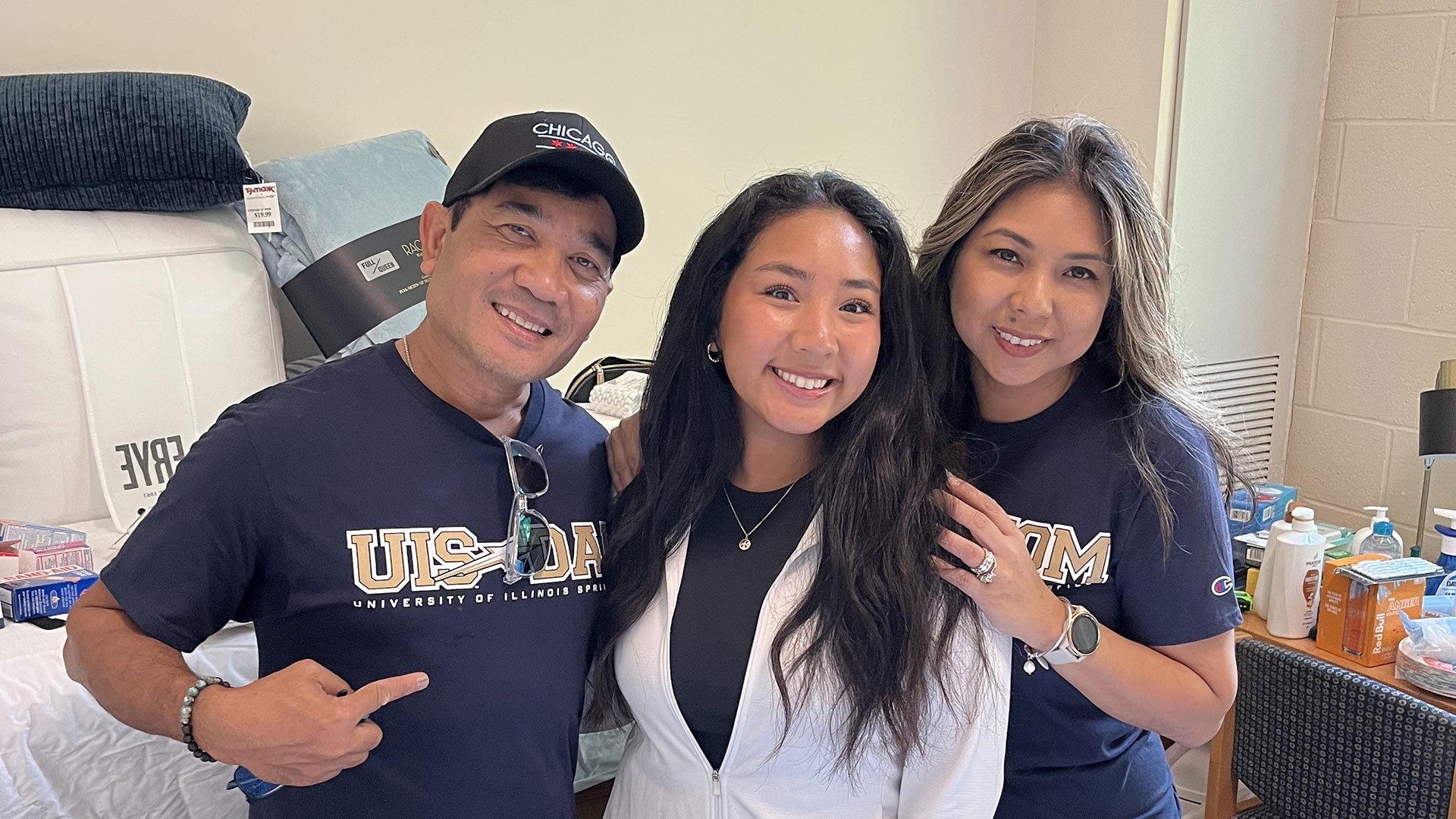 Smiling group of three in UIS attire indoors.