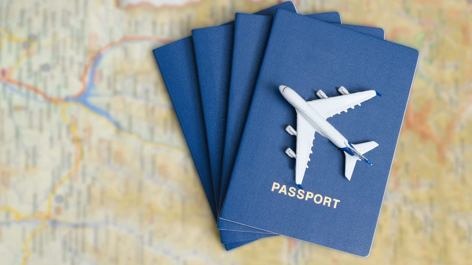 a stack of passports on top of a map with a toy plane on top of them