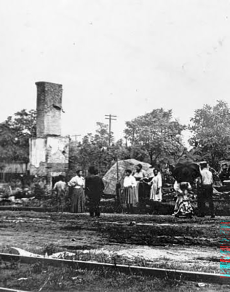 People standing near a tall, damaged building with trees in the background.