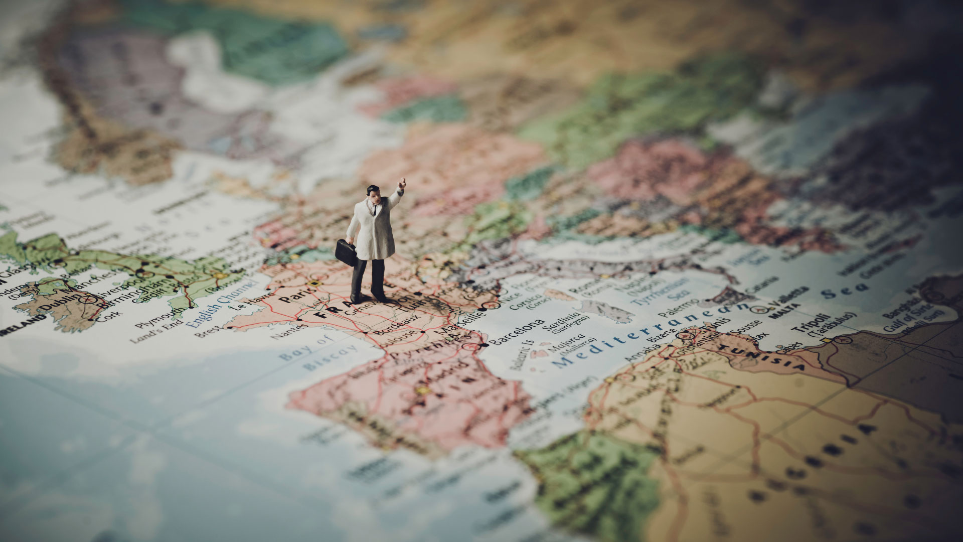 a toy male traveller standing on a map