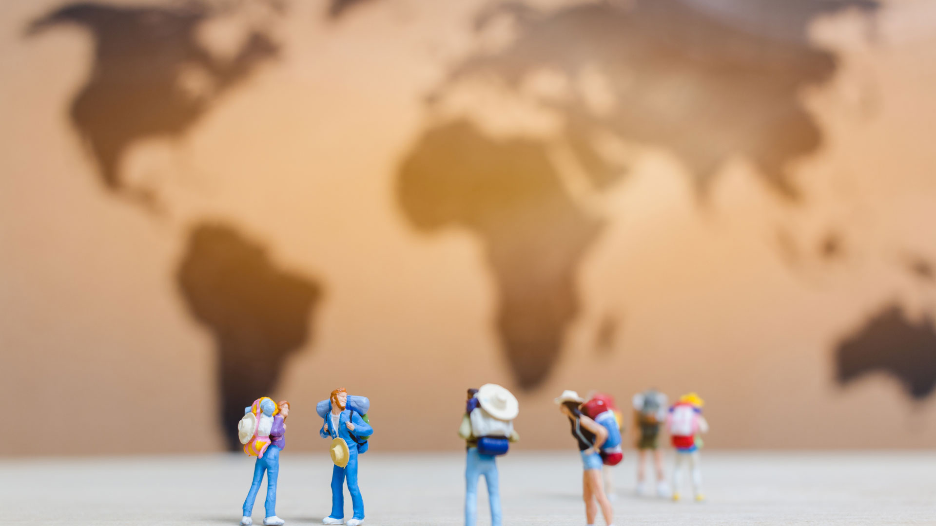 a bunch of toy traveller figurines standing in front of a world map