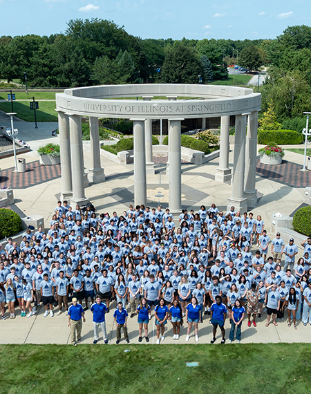Large group of people in front of a circular monument with columns.