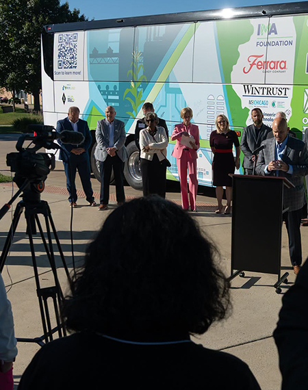 People standing in front of a brightly colored bus, with camera setup in foreground.