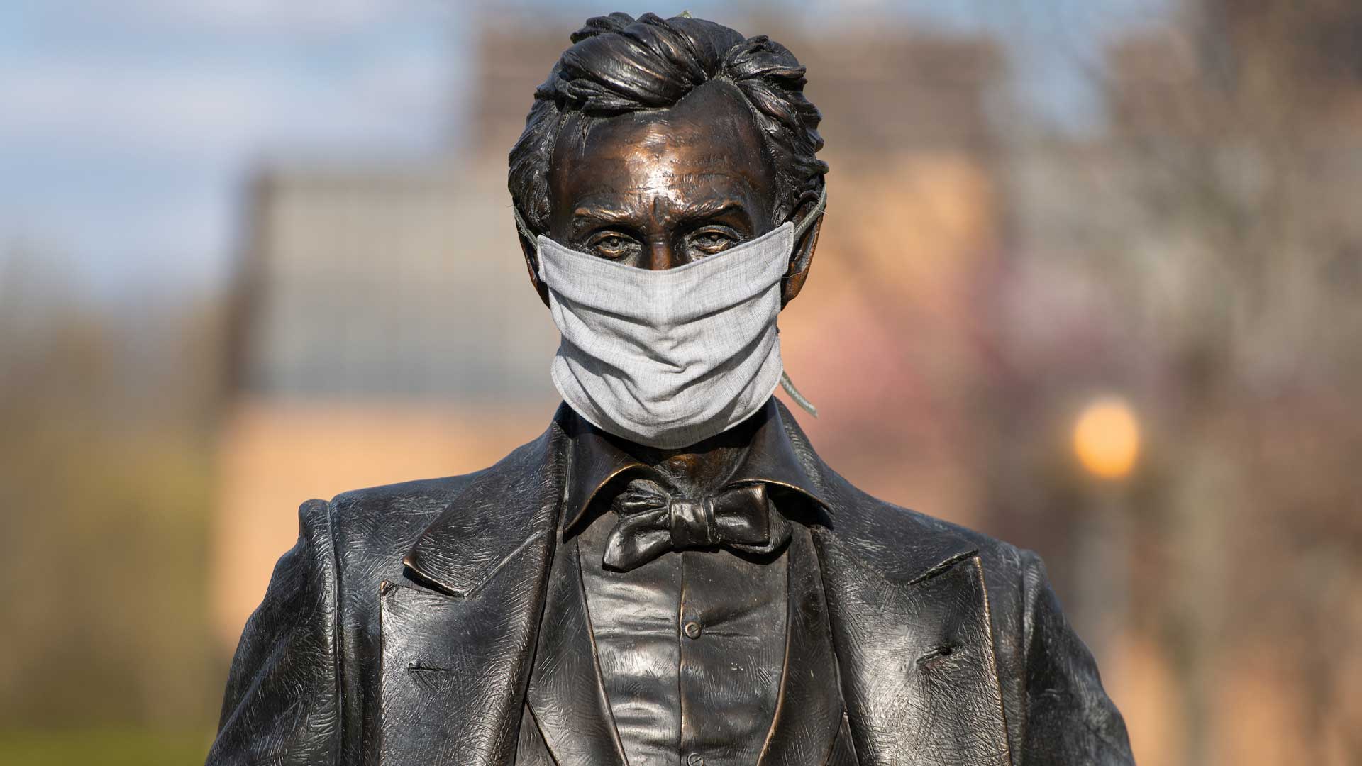 a statute of Abraham Lincoln on campus wearing a mask