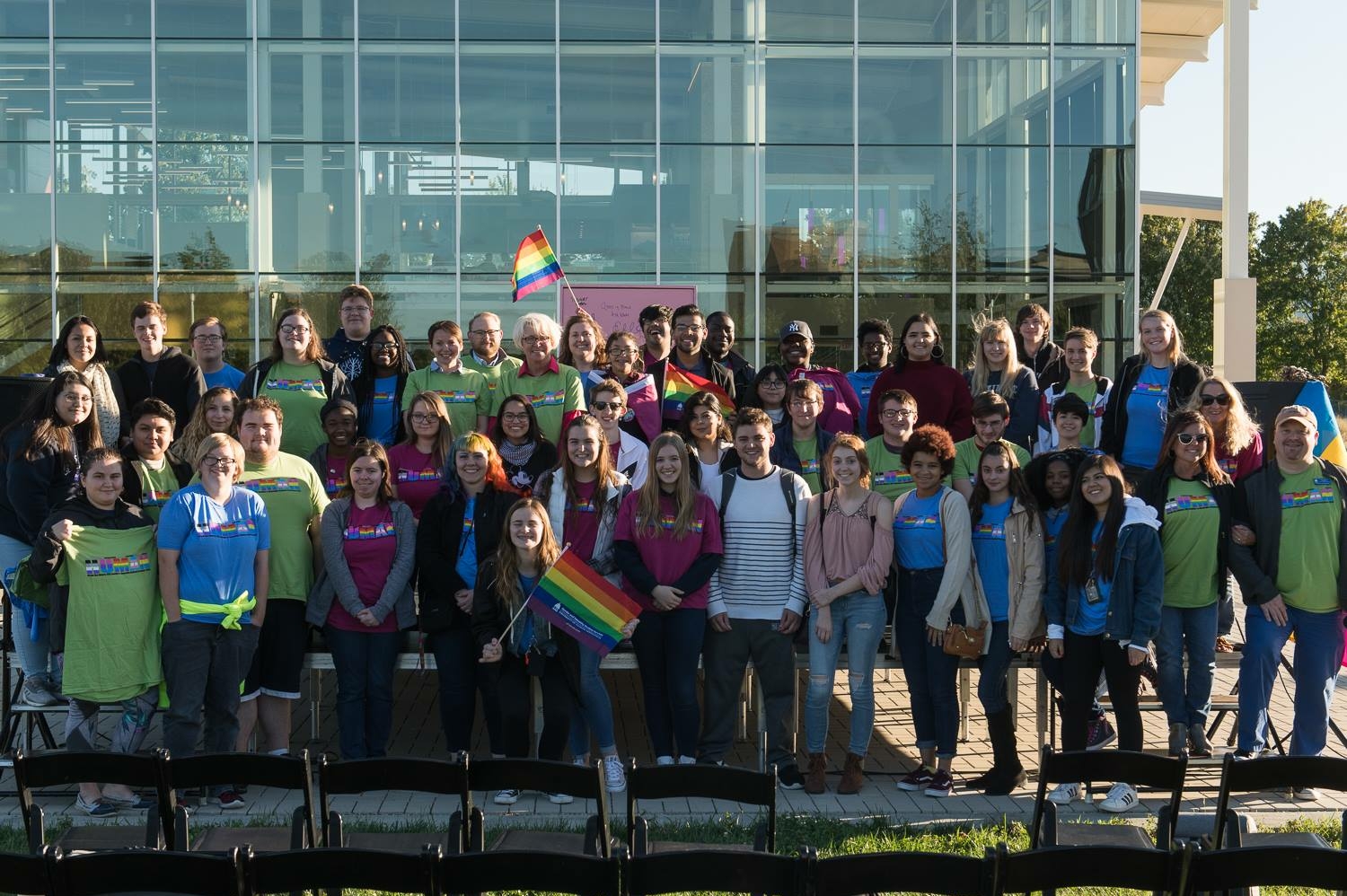 Group of people in colorful shirts holding rainbow flags.