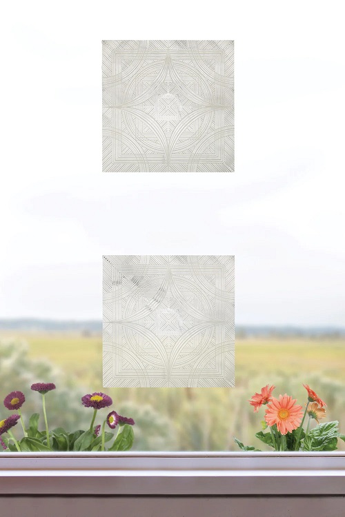 Photo of two small square decals on a window with a windowstill at the bottom and prairie behind it.