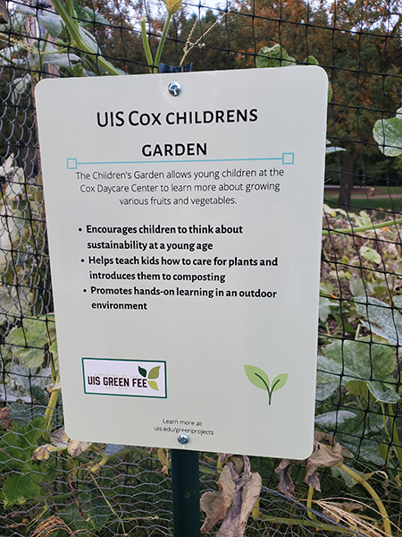 A sign that says "UIS Cox Children's Garden" and lists benefits of the garden
