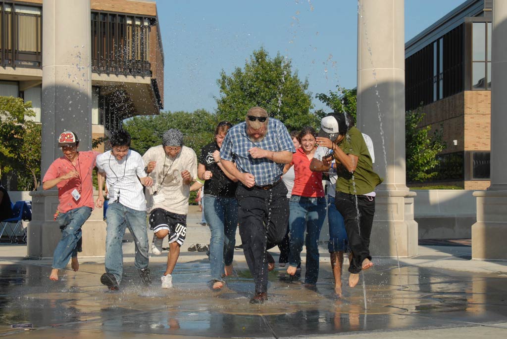 people running through the colonnade's water fountain