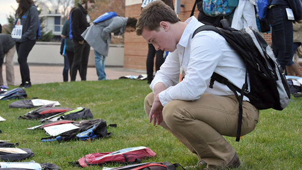 Student looking at a backpack on the ground