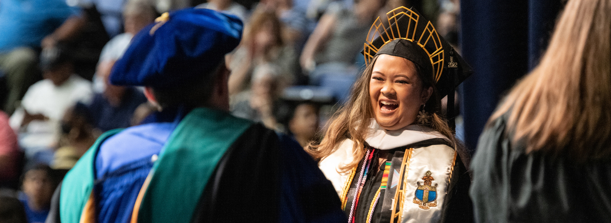 student joyfully receiving her diploma from professor